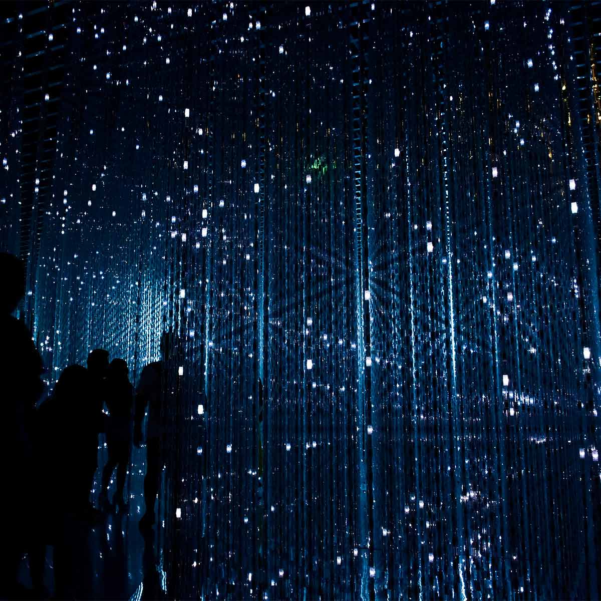 Silhouettes of people under a starry sky with vertical light patterns