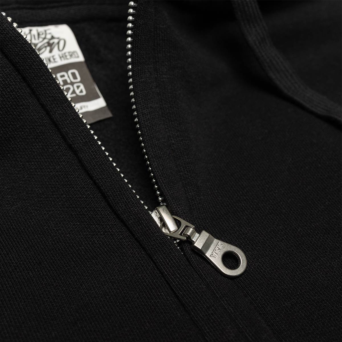 Close-up of a black zipper on a hoodie with a brand label.