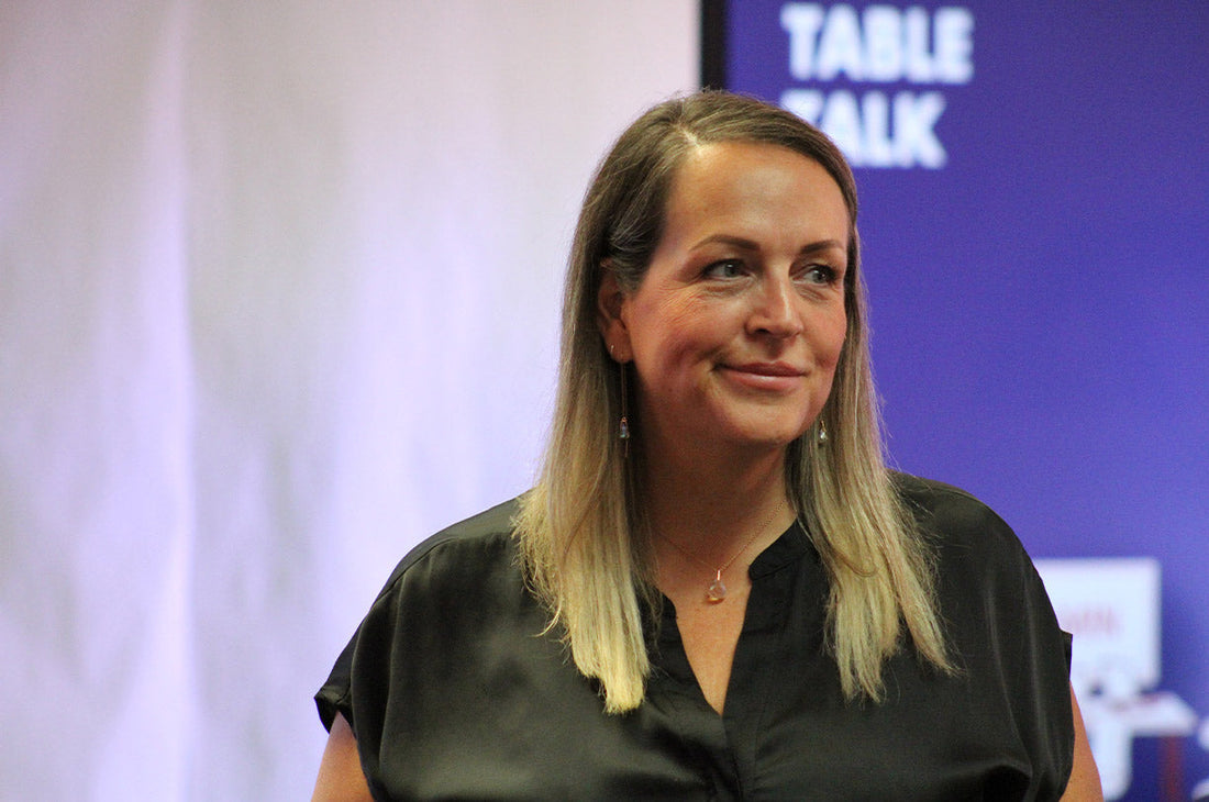 portrait style photo of a blonde woman smirking with a blue and white background