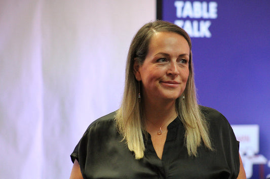 portrait style photo of a blonde woman smirking with a blue and white background