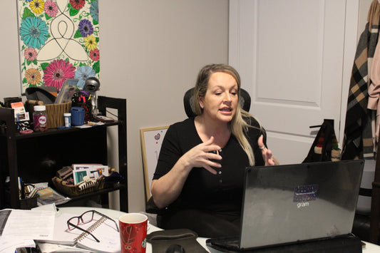 a woman sitting in her office and speaking with a client via video chat