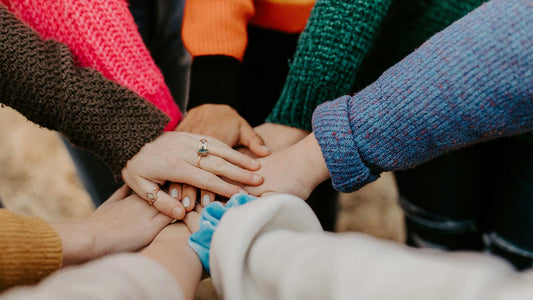 A team of people with their hands in the center
