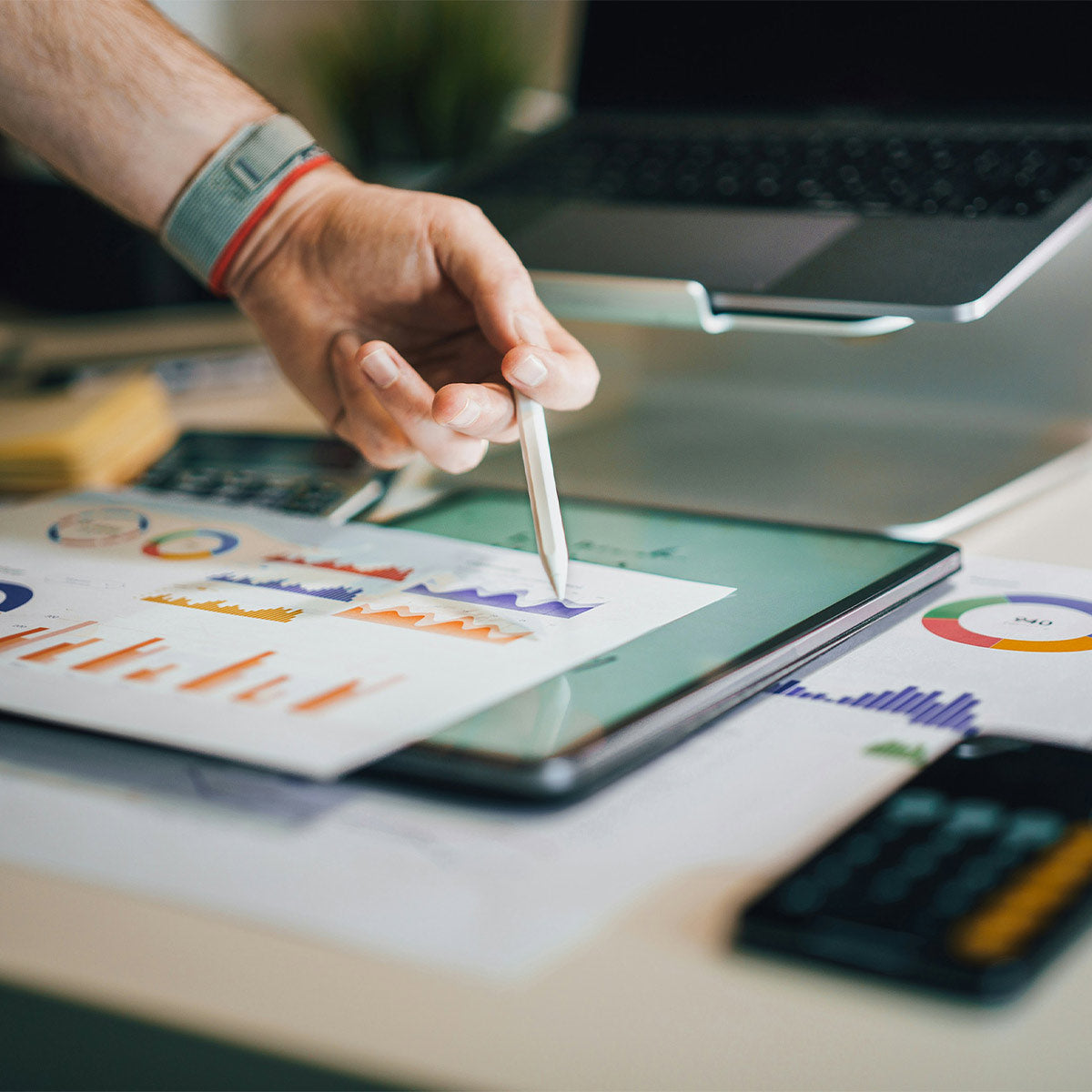 Person using a stylus on a tablet with graphs and charts displayed