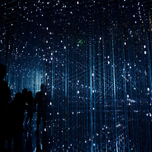 Silhouettes of people under a starry sky with vertical light patterns