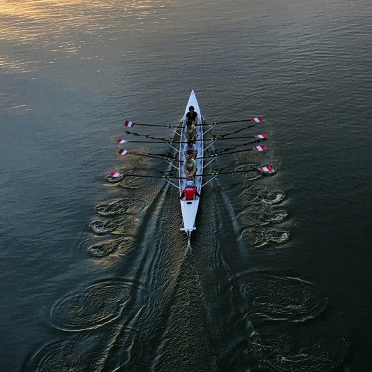 Rowing team in a boat on a body of water during sunset