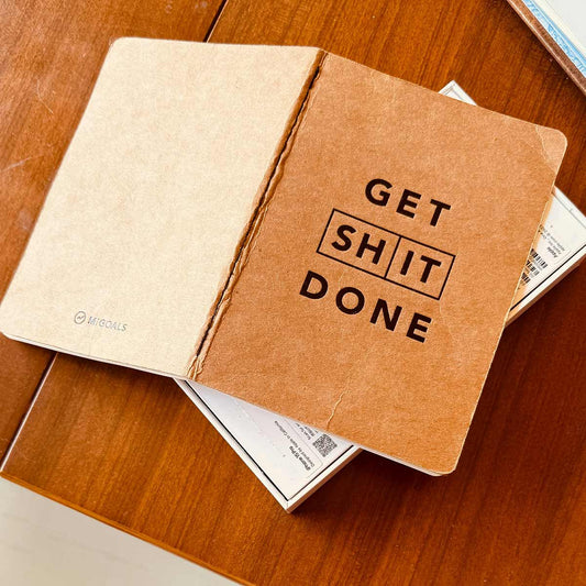 Notebook with 'GET SH IT DONE' text on a wooden surface