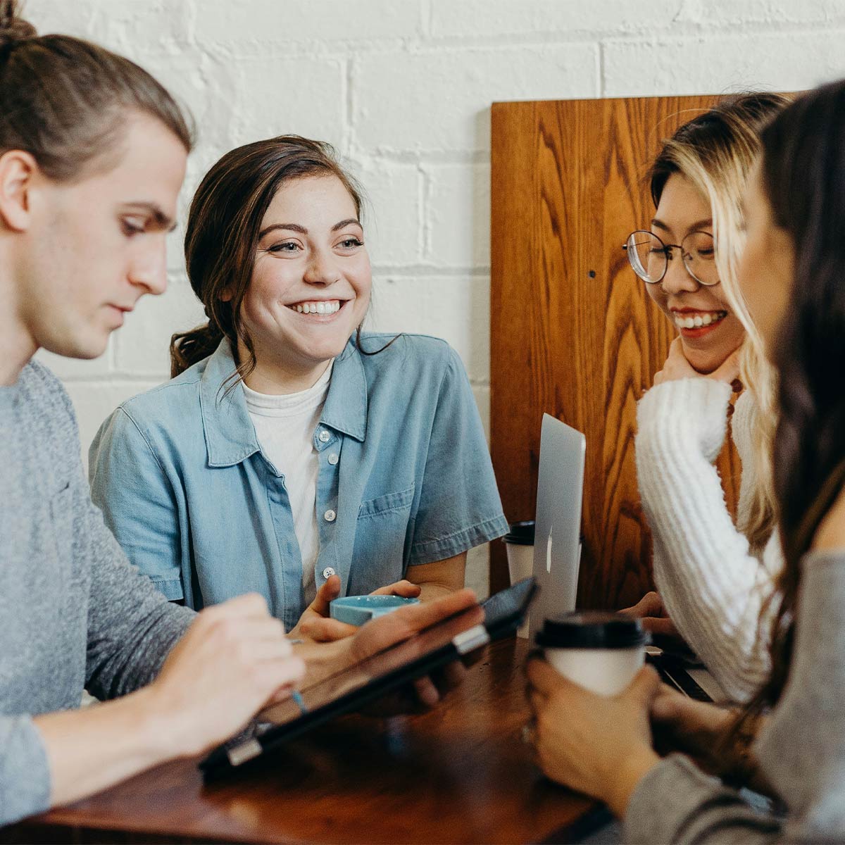 Group of people sitting around a table, smiling and interacting.