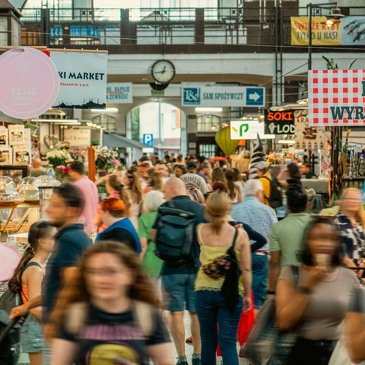 Crowded indoor market with various shops and signs.