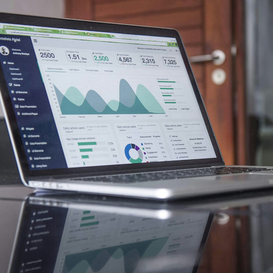 Laptop displaying a business analytics dashboard on a reflective surface.