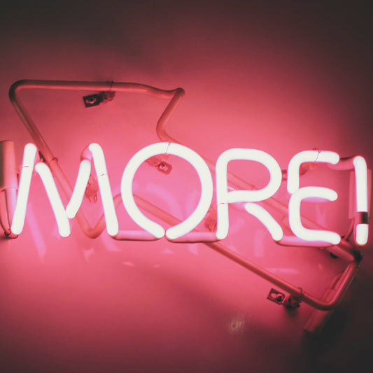 Neon sign with the word 'MORE!' on a pink background