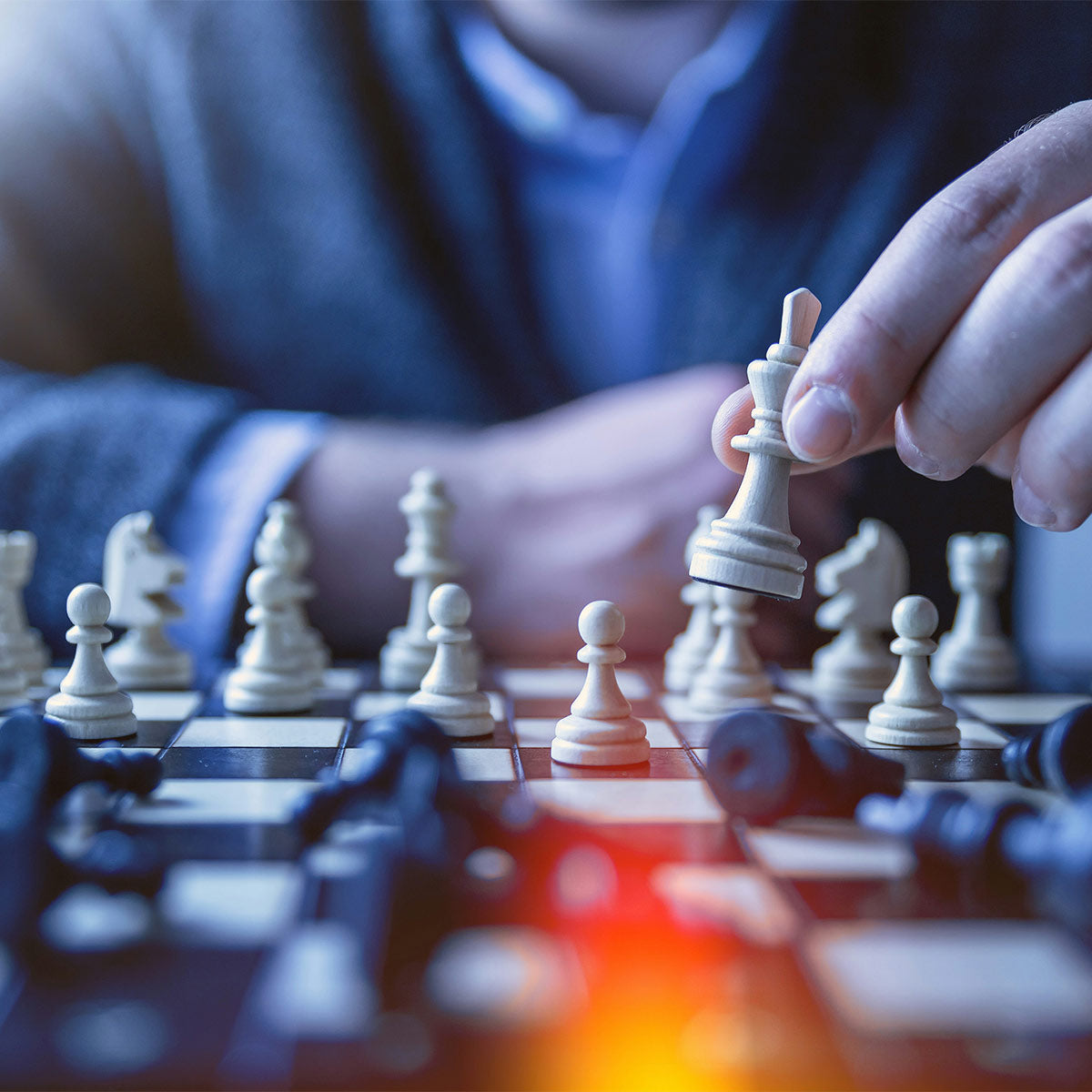 Person playing chess with a focus on a white king piece.
