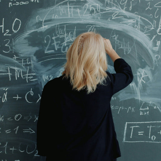 Person writing on a chalkboard filled with mathematical equations