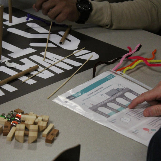 Person working on a project with wooden blocks and colorful sticks on a table.